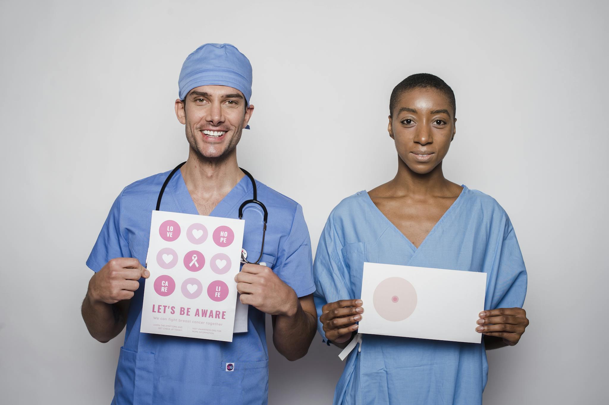 Healthcare professionals in scrubs promoting breast cancer awareness with informative posters.